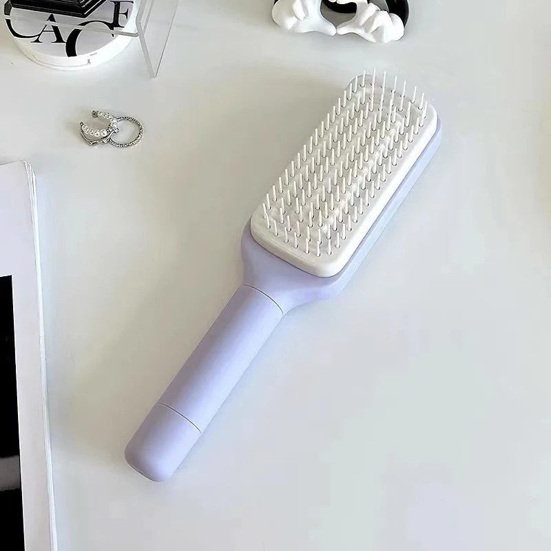 Light purple hairbrush on a white surface with jewelry in the background